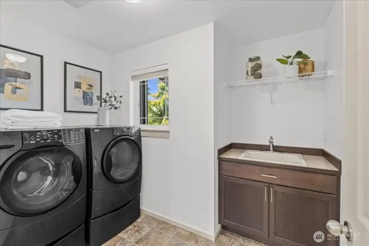 Spacious upper-level laundry room with built-in utility sink, cabinet storage, and dedicated workspace. Functional design adds convenience for everyday household tasks.