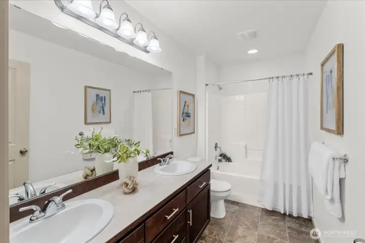 Full bathroom featuring dual-sink vanity, large mirror, and tub/shower combination—functional layout with ample counter space and storage.
