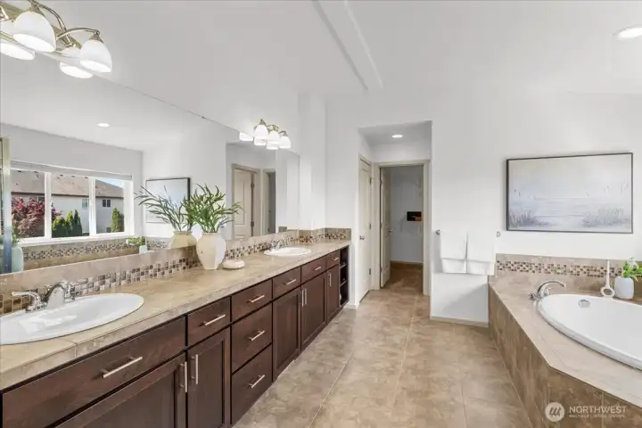 Spa-inspired primary bath featuring dual vanities, extensive cabinetry, oversized soaking tub, and generous natural light. Spacious layout designed for everyday comfort and convenience.