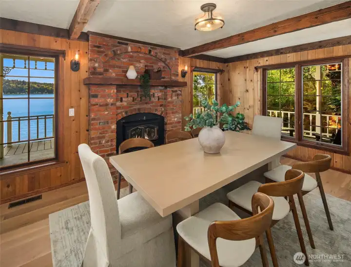 Framed by rich wood paneling and anchored by a handsome brick fireplace, the dining room offers a warm and inviting setting for entertaining, with tranquil views toward Quartermaster Harbor.