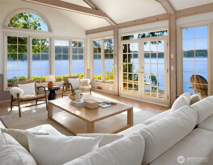 Vaulted ceilings, exposed trusses, French doors, and walls of windows frame sweeping views across Quartermaster Harbor.