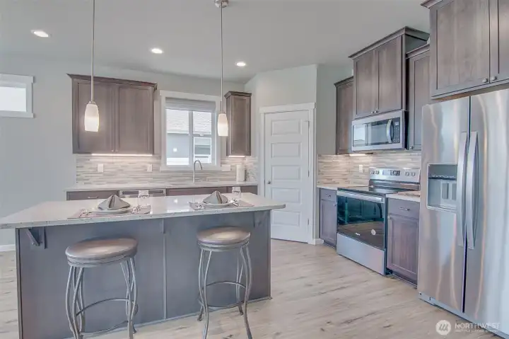 Kitchen with Island, Engineered quartz counters, under cabinet lighting, custom tiled back splash, Stainless Steel Whirlpool appliances, and Step-In Pantry.