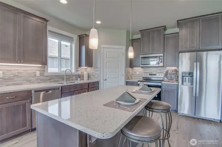 Kitchen with Island, Engineered quartz counters, under cabinet lighting, custom tiled back splash, Stainless Steel Whirlpool appliances, and Step-In Pantry.