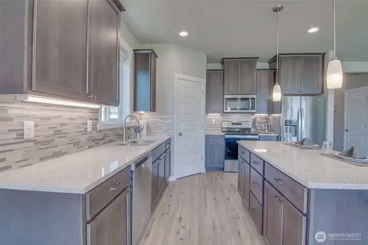 Kitchen with Island, Engineered quartz counters, under cabinet lighting, custom tiled back splash, Stainless Steel Whirlpool appliances, and Step-In Pantry.