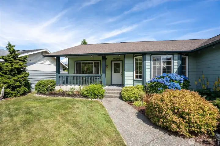 Front exterior with covered entry and mature landscaping.