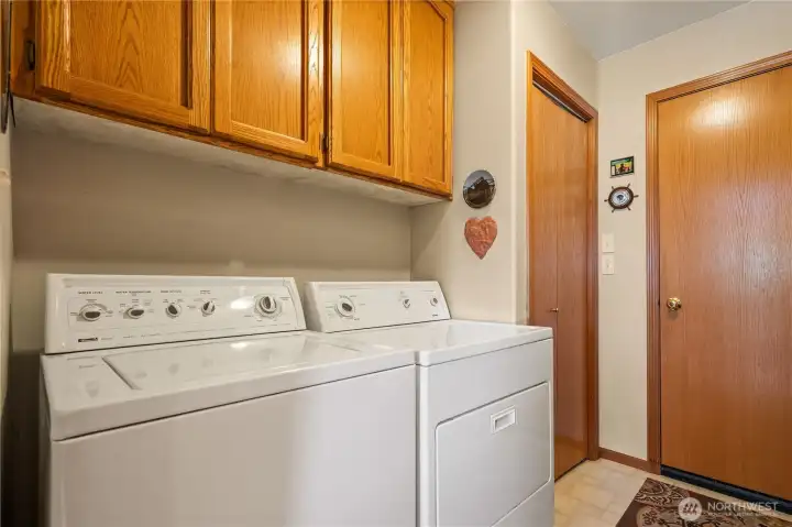 Dedicated laundry room with overhead storage cabinets.