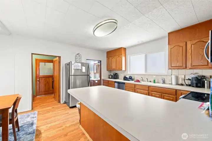 View of kitchen from dining area. Door to left goes to the utility room and to the right of the refrigerator is the downstairs bathroom. View of kitchen from dining area. Door to left goes to the utility room and to the right of the refrigerator is the downstairs bathroom.