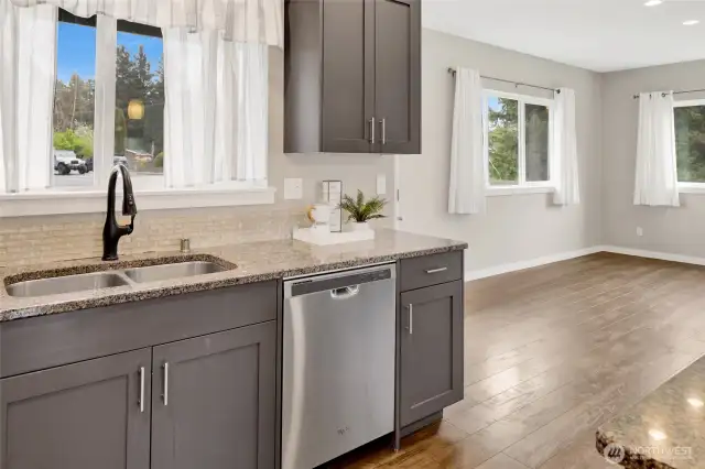 Granite countertop with tile backsplash and stainless steel sink and appliances.