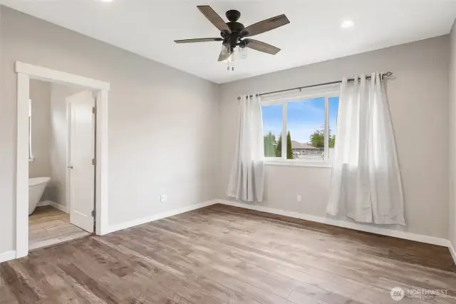 Primary bedroom with lighted ceiling fan, walk-in closet, and soaking tub and separate shower, and toilet closet.