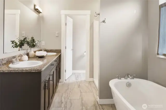 Primary bath with soaking tub, shower, dual vanity, toilet closet, and tile floors.