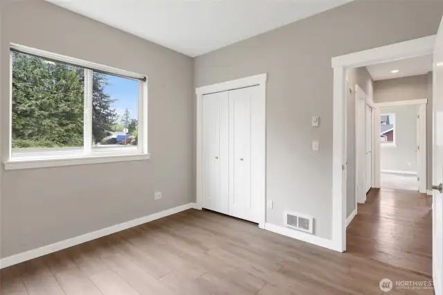 Third bedroom with new LVP flooring looking to the hall with the bathroom separates the bedrooms for privacy, and hallway entry closet.