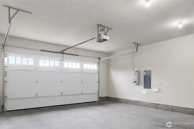 Garage with the solar panel on the wall. There is a door to the side of the home with sidewalk to the driveway.