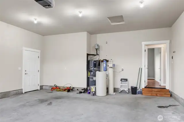 Garage with door to the side yard, and the water filtration system, hot water tank, and the door to the home.