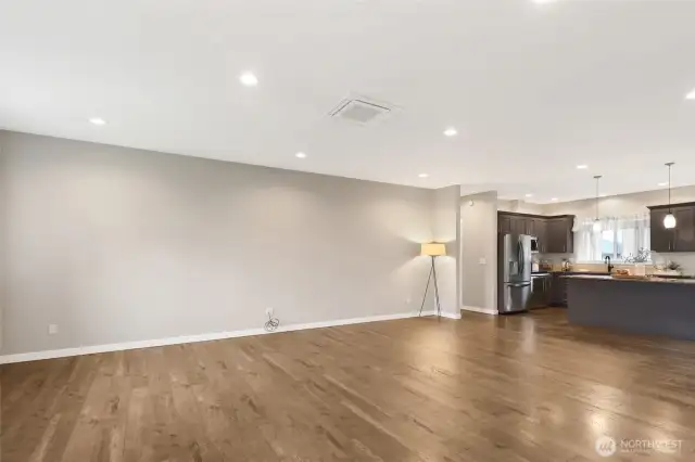 Large living room with easy care laminate wood floors. The hallway to the left takes you to the garage door entry with access to the kitchen, the laundry room straight ahead, and the primary bedroom.