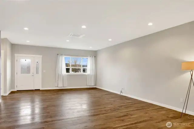 Living room looking toward the front door and large windows flood the room with light.