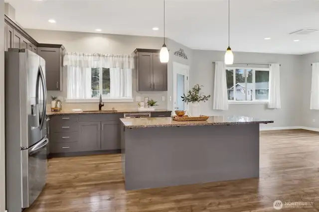 Nicely appointed kitchen with island with eating bar with granite countertops, and plenty of cabinet storage. The stainless steel appliances are included. The kitchen window looks out onto the backyard and the dining room.