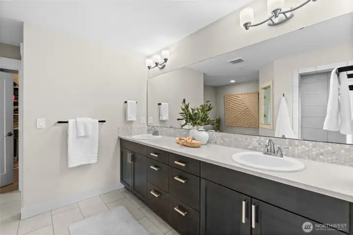 The five-piece bathroom features dual vanities, a walk-in tiled shower, a soaking tub, a private water closet, and an adjoining walk-in closet—comfort and thoughtfulness with every detail.