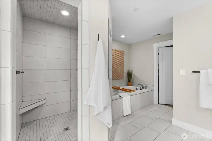 A large walk in fully tiled shower includes a shower chair and several built in shelves to hold all your shower essentials.