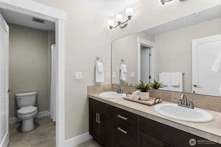 A shared full bathroom on the upper level includes expansive counter space and cabinetry.