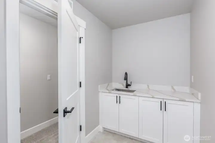 The deluxe laundry room is complete with a sink, counter and 2 walls of cabinets.