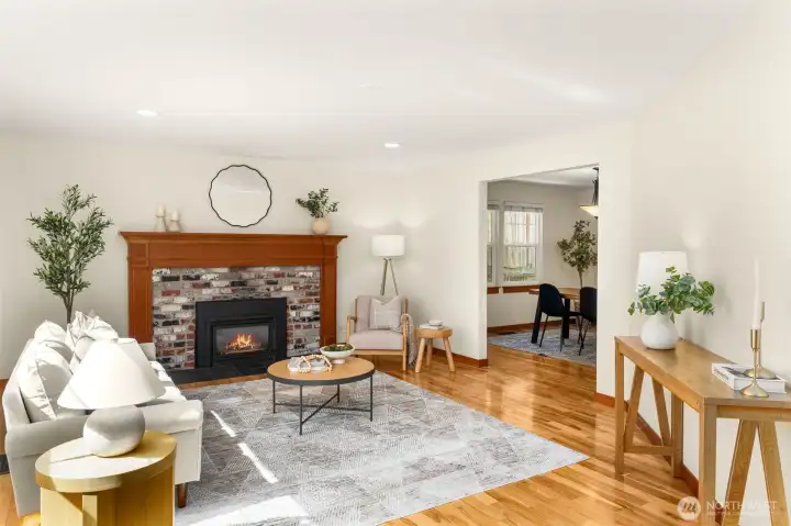 Light-filled and inviting, this spacious living room offers the perfect setting for both everyday living and entertaining. Warm hardwood floors, fresh interior paint, and a classic brick fireplace with a wood mantel create a cozy yet refined atmosphere