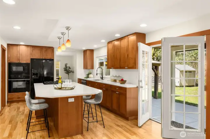 This well-appointed chef's kitchen offers quartz countertops, rich custom cabinetry, and a generous island with bar seating. Thoughtfully designed with a large walk-in pantry and French doors.