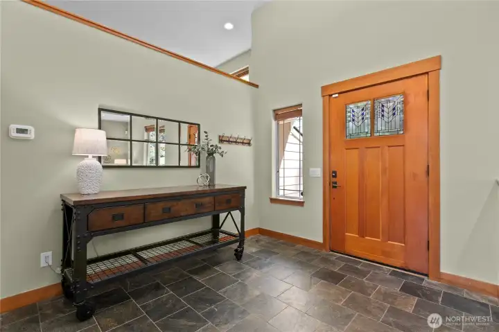 Inviting foyer with wood entry door, slate tile floors, and functional space for everyday arrivals and departures.
