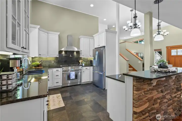 Chef-inspired kitchen with custom cabinetry, stone surfaces, stainless appliances, and dramatic ceiling height.