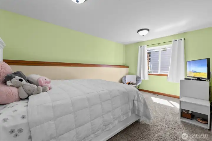 Spacious third bedroom with large window, soft natural light, and wooded outlooks.