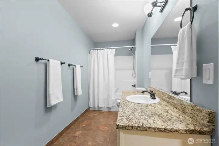 Full bathroom with granite counters, updated fixtures, and generous vanity space.