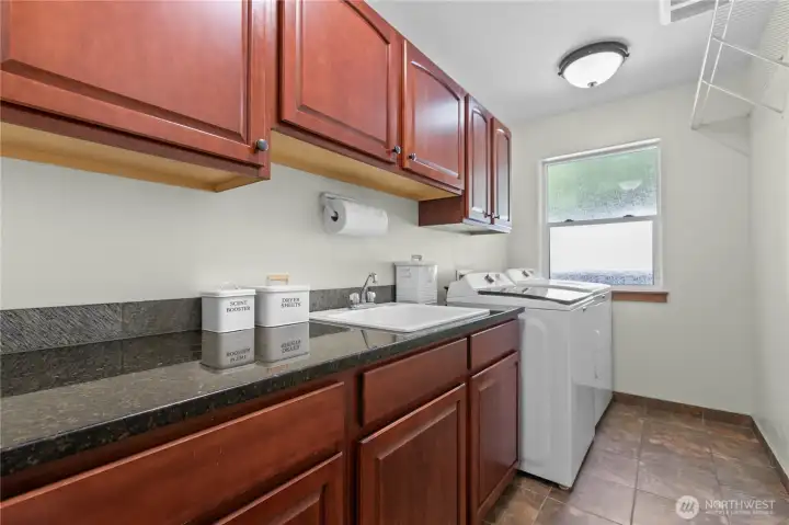 Spacious laundry room with brand new washer and dryer, extensive cabinetry, utility sink, and workspace for everyday organization.