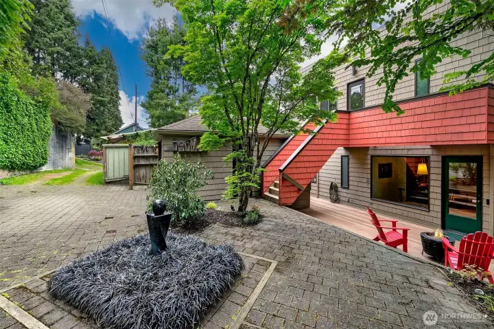 A view of the detached one car garage with E-car charger. Back deck, patio and entrance into the kitchen.