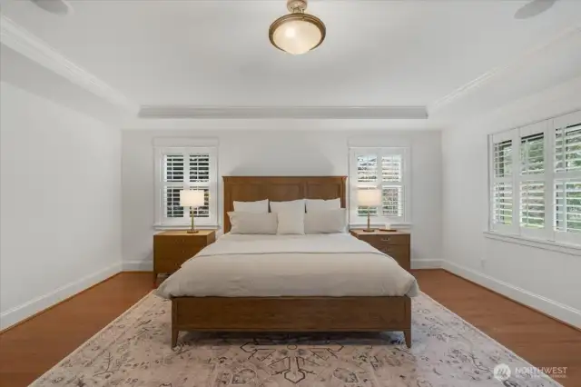 Large Primary Suite features hardwood floors and and inset tray ceiling.