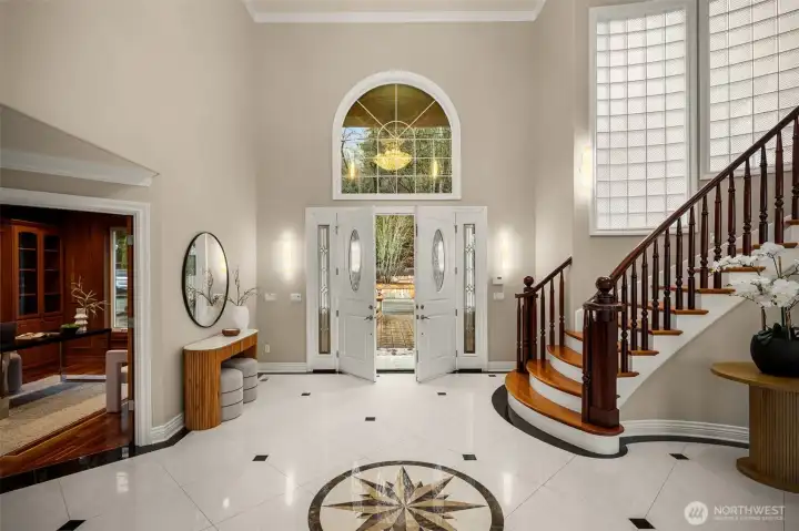 Elegant two-story foyer with sweeping staircase and marble inlay flooring.