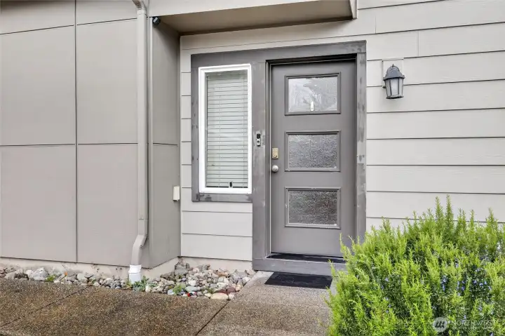 Charming front entry with modern siding, private door, and tasteful landscaping