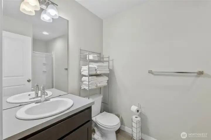 Pristine first-floor bathroom with modern vanity, clean tilework, and quality fixtures and roll-in shower