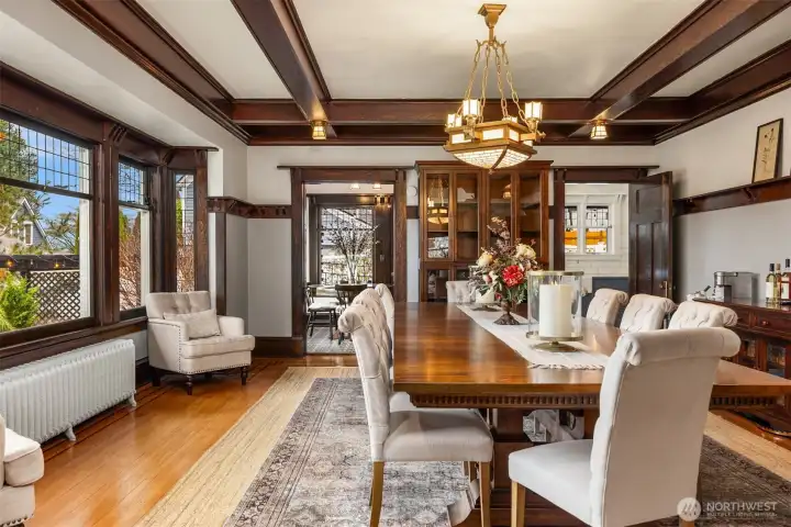 A charming breakfast nook blends historic character with modern function. Original wood-trimmed windows, patterned tile floors, and a cozy built-in feel create an inviting space for morning coffee or casual meals, seamlessly connected to the kitchen while overlooking the garden beyond.