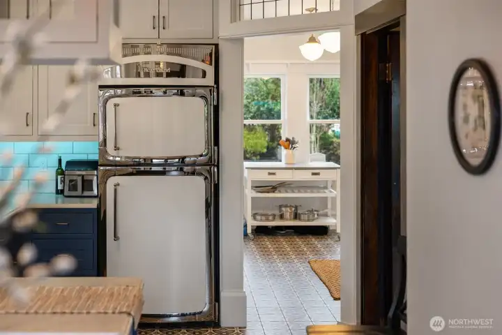 A charming secondary prep space and "hot" kitchen enhances the kitchen’s versatility. Patterned tile floors, natural light, and additional storage create a functional extension ideal for entertaining, baking, or everyday organization.
