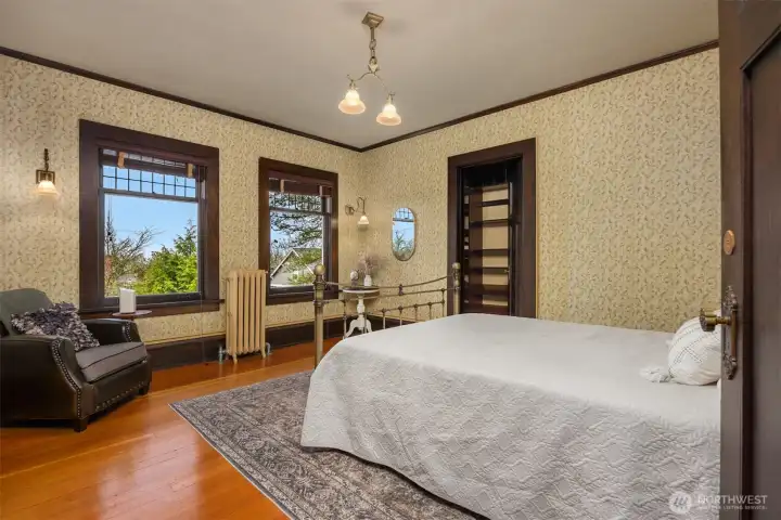 This inviting bedroom highlights vintage wallpaper, walk-in closet, and warm wood accents. A charming space that feels personal, comfortable, and rich with character.