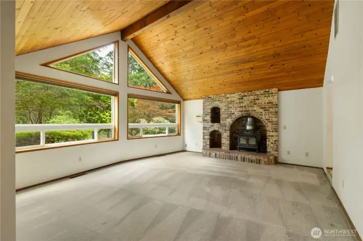 This sunk-in living room does not disappoint with its Knotty Pine ceiling and impressive brick woodstove insert.