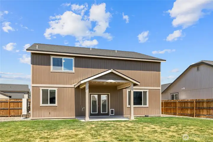 Fenced back yard with sprinklers and covered patio