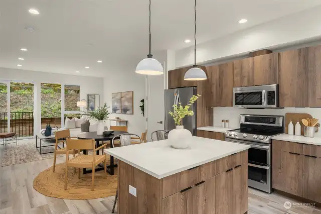Kitchen features a quartz island, stainless steel appliances, pantry and modern cabinetry.