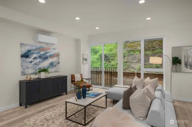 Livingroom features warm vinyl plank flooring, minisplit and recess lighting.
