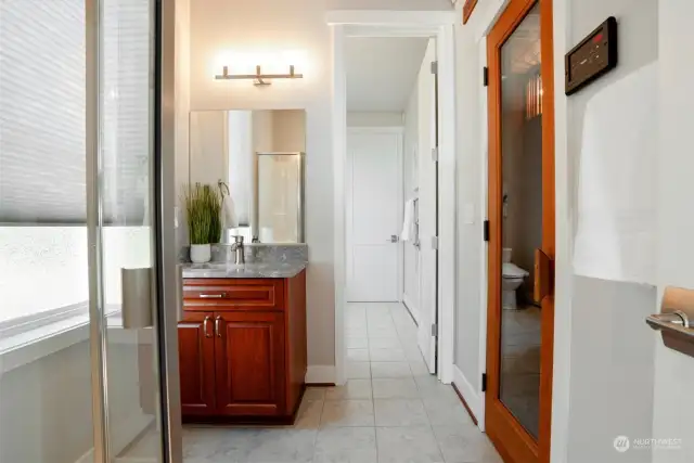 This attached bath to the 2nd main-floor bedroom is set up so smartly. Each room is equipped with a sink. This view shows the shower and through the door is the toilet. The glass door leads to your private sauna.