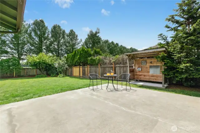 Backyard is private and features a large patio, covered cooking space, and mature landscaping