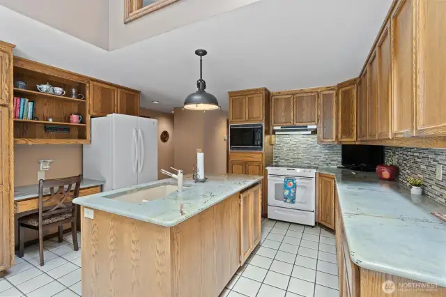 Updated kitchen featuring a desk area, granite countertops, tile backsplash, Blanco sink, and all kitchen appliances will stay