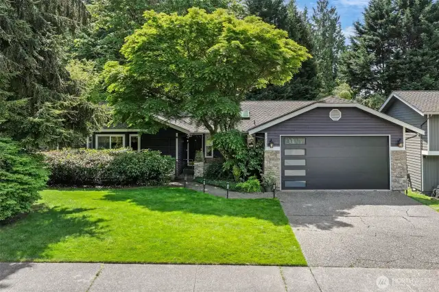 Nestled beneath mature trees, this charming rambler offers exceptional curb appeal with a blend of contemporary and natural design. The modern garage door, stone accents, and manicured landscaping welcome you home to this peaceful English Hill setting within the sought-after Northshore School District.