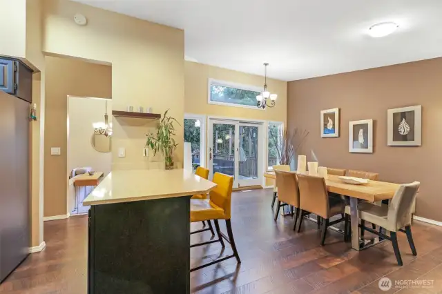An alternate view shows the harmonious flow between kitchen, dining, and outdoor access—ideal for hosting or unwinding at home. Rich wood floors and elevated ceilings enhance the spacious feel throughout.