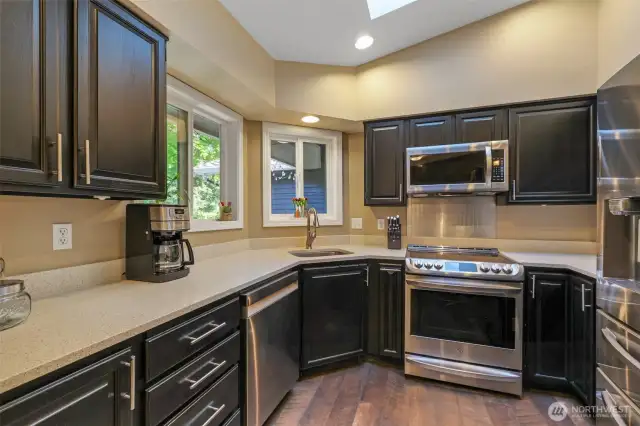 Enjoy preparing meals with a view in this thoughtfully designed kitchen. Multiple windows frame the surrounding greenery, while ample counter space and cabinetry offer both style and utility.