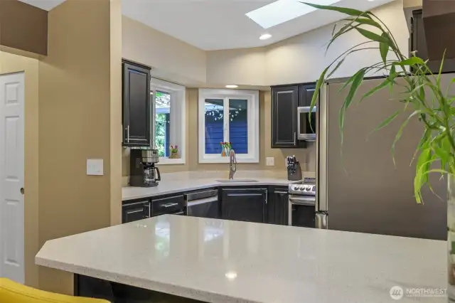 The spacious countertop and breakfast bar serve as a functional extension of the kitchen, perfect for quick meals, entertaining guests, or setting up a snack station during gatherings.